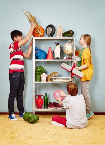 Drei Kinder bestücken ein Regal mit verschiedenen Dingen